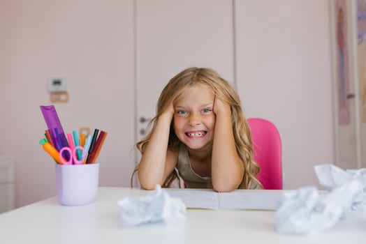 Funny Caucasian girl of seven years old at her desk at home or at school tired of doing homework photo