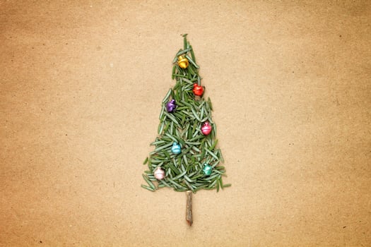 Green srpuce needles Christmas tree pattern with jingle bells on craft recycled paper. Ecological minimal design for holiday postcard. Eco friendly, zero waste, diy, nature concept. Flatlay, top view photo