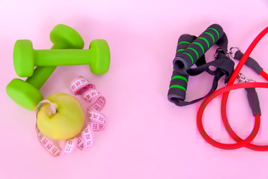 A green apple, and a centimeter measuring tape on a pink background. Sports, sports nutrition, healthy eating, diet. Space for the text. photo