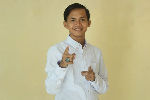 young asian man in white shirt pointing forward giving vote or agree  on yellow background photo