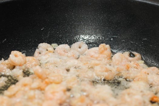 Close-up of peeled, shelled boiled shrimp being fried photo