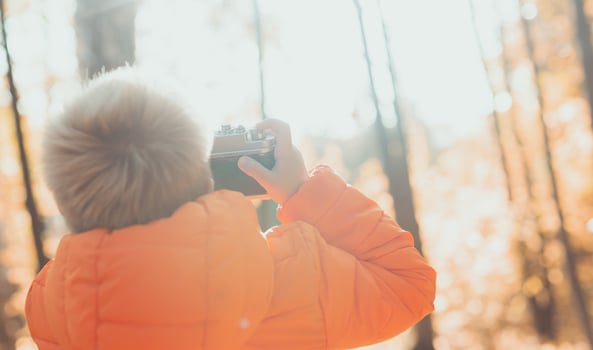 Boy with retro camera taking pictures outdoor in autumn nature. Leisure and photographers concept photo