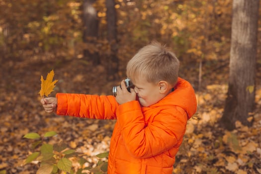 Boy with retro camera taking pictures outdoor in autumn nature. Leisure and photographers concept photo