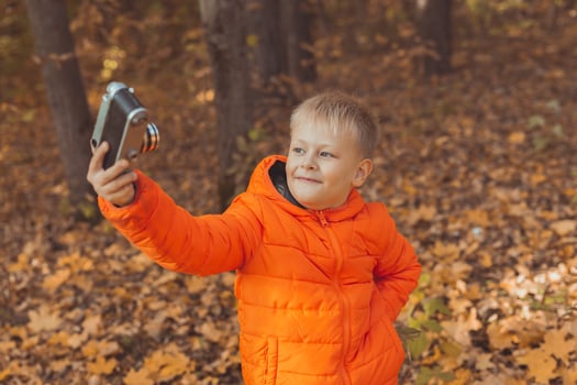 Boy in park in autumn taking selfie photo. Fall and leisure concept. photo