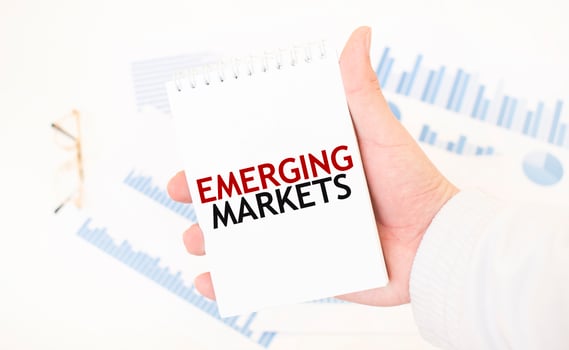 Businessman holding a white notepad with text EMERGING MARKETS, business concept photo