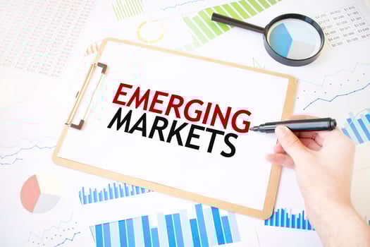 Text EMERGING MARKETS on white paper sheet and marker on businessman hand on the diagram. Business concept photo