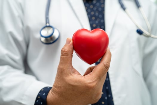 Doctor holding a red heart in hospital ward, healthy strong medical concept. photo