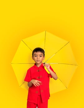 boy fashion  wearing a Chinese-style shirt holding a yellow umbrella poses for a photo shoot.