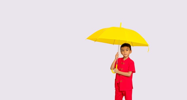 boy fashion  wearing a Chinese-style shirt holding a yellow umbrella poses for a photo shoot.