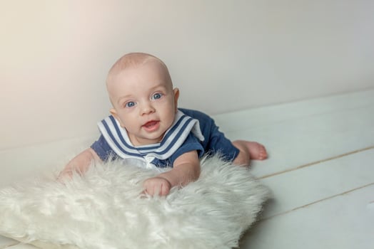 Infant baby boy lies on pillow on white bedroom background photo