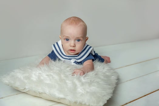 Infant baby boy lies on pillow on white bedroom background photo