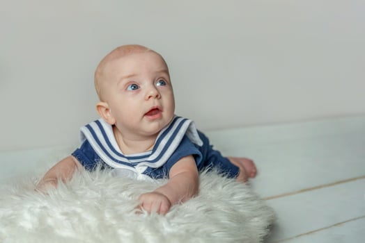 Infant baby boy lies on pillow on white bedroom background photo
