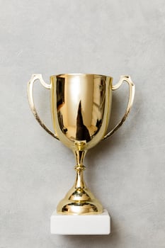 Simply flat lay design winner or champion gold trophy cup on concrete stone grey background. Victory first place of competition. Winning or success concept. Top view copy space. photo