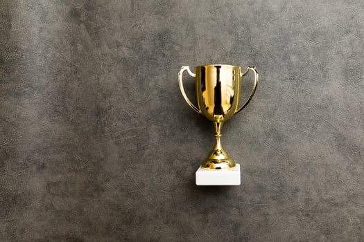 Simply flat lay design winner or champion gold trophy cup on concrete stone grey background. Victory first place of competition. Winning or success concept. Top view copy space. photo