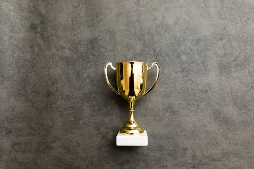 Simply flat lay design winner or champion gold trophy cup on concrete stone grey background. Victory first place of competition. Winning or success concept. Top view copy space. photo