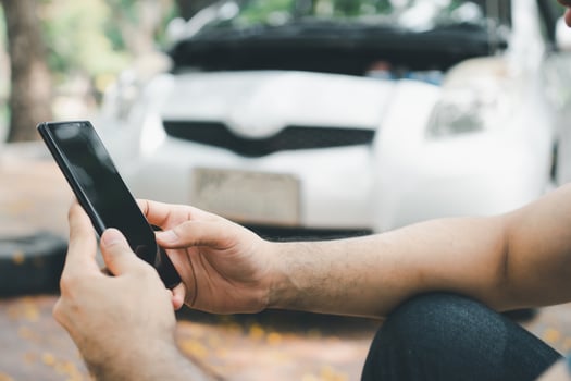 Asian man using smartphone for assistance after a car breakdown on street. Concept of vehicle engine problem or accident and emergency help from Professional mechanic photo