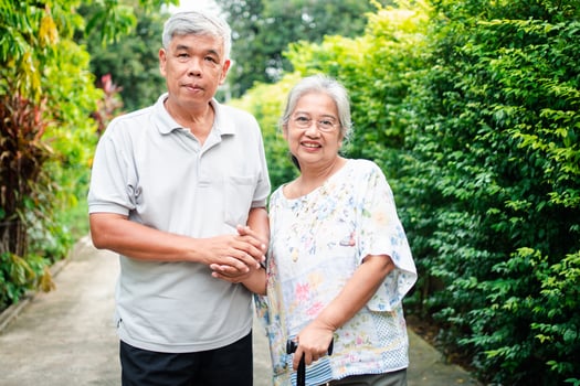Happy senior couple walking together in the garden. Old elderly using a walking stick to help walk balance. Concept of  Love and care of the family And health insurance for family photo