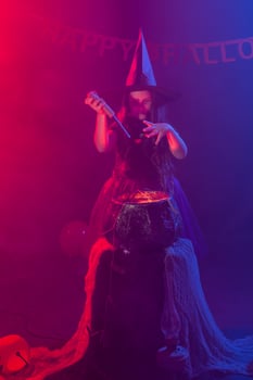 Little witch child cooking potion in the cauldron on Halloween. photo