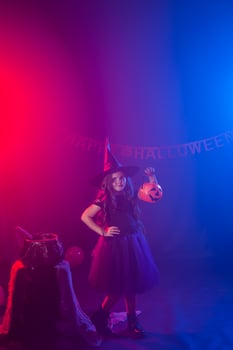 Little girl holds pumpkin jack on Halloween holiday. Kid girl wear witch costume. Fantasy, fairy tale and masquerade concept. photo