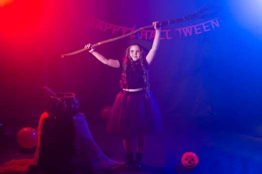 Little girl holds broom on Halloween holiday. Kid girl wear witch costume. Fantasy, fairy tale and masquerade concept. photo