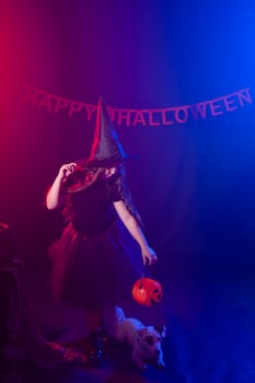 Funny child girl in witch costume for Halloween with pumpkin Jack and dog. photo