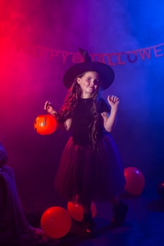 Funny child girl in witch costume for Halloween with pumpkin Jack. photo