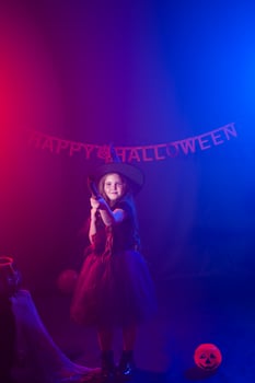 Little girl holds broom on Halloween holiday. Kid girl wear witch costume. Fantasy, fairy tale and masquerade concept. photo