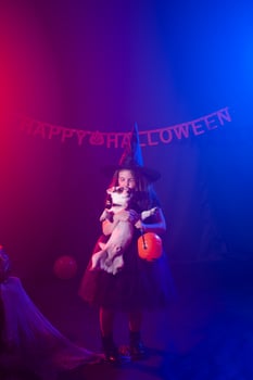 Funny child girl in witch costume for Halloween with pumpkin Jack and dog. photo