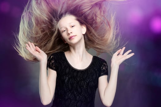 Against a purple background, a beautiful teenage girl flapped her hair. photo