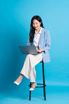 Asian businesswoman portrait sitting on chair, isolated on blue background photo