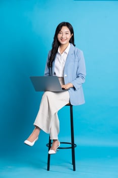 Asian businesswoman portrait sitting on chair, isolated on blue background photo