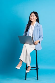 Asian businesswoman portrait sitting on chair, isolated on blue background photo