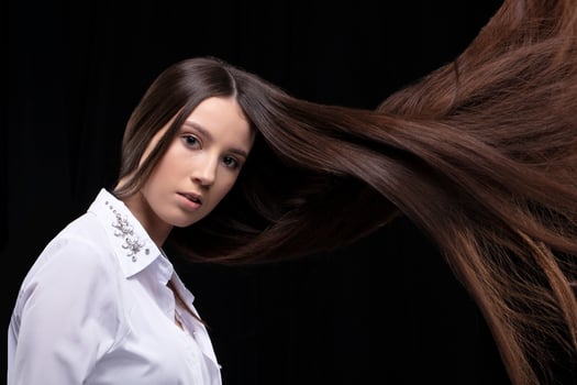 Beautiful brunette with long flying hair on a dark background. photo
