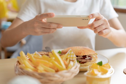 restaurant owner takes a picture of the food on the table with a smartphone to post on a website. Online food delivery, ordering service, influencer, review, social media, share, marketing, interest. photo