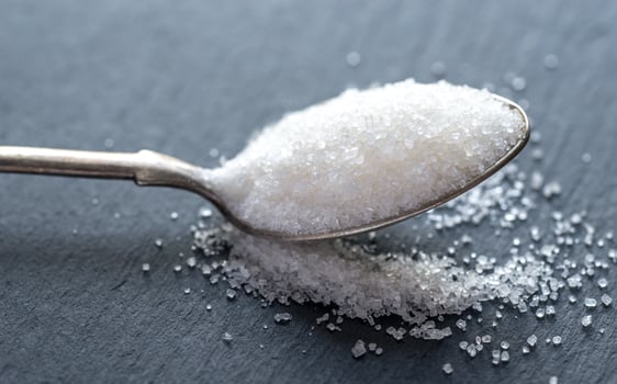 Spoon with white sugar on the dark background photo