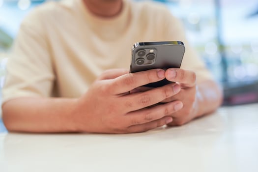 Relaxed young asian man using smart phone  spending time checking news social media. photo