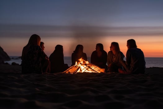 A photo that captures a group of friends gathered around a beach bonfire.