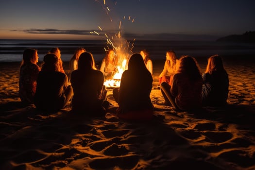 A photo that captures a group of friends gathered around a beach bonfire.