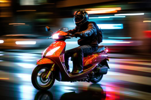 Close - up image, a delivery man is riding his scooter motorcycle through the city streets at night. photo