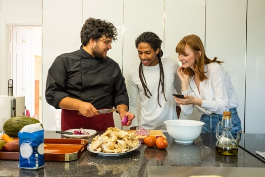 chef teaching a young couple of different breeds how to cook photo