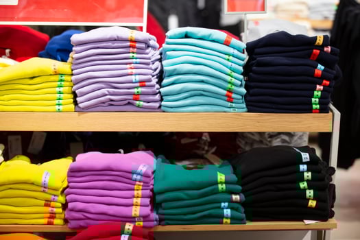 There are stacks of knitted sweaters, folded longsleeves or T-shirts on a store shelf. Selling clothes in a store. photo