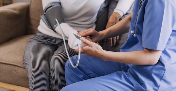 Homecare nursing service and elderly people cardiology healthcare. Close up of young hispanic female doctor nurse check mature caucasian man patient heartbeat using stethoscope during visit photo