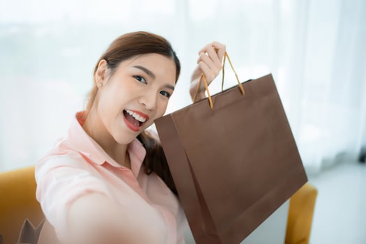 Happy asian woman taking selfie with shopping bag in the shop's VIP lounge photo