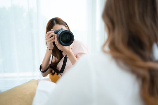 Beautiful asian woman photographer taking picture with professional camera at home photo