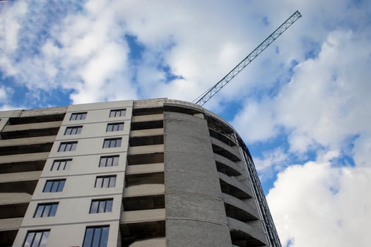 Construction of a Residential New House is Underway at the Construction Site of a Residential Complex. Background with Construction Site with Crane and Blue Sky. City Development. City Skyline. photo