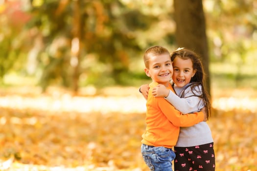 Children playing with autumn fallen leaves in park photo