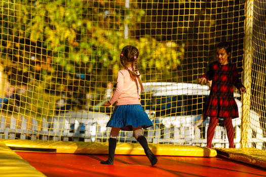 Happy school girl jumping on trampoline in the autumn park photo