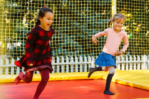 Happy school girl jumping on trampoline in the autumn park photo