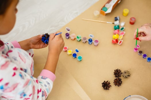 Cute little girl coloring a natural cone fir to create a flower, set of brushes, paints, natural autumn materials, create fun and easy with children, diy for kindergarten photo