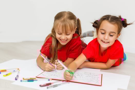 family, leisure and childhood concept - happy sisters lying on floor and drawing and doing homework at home photo